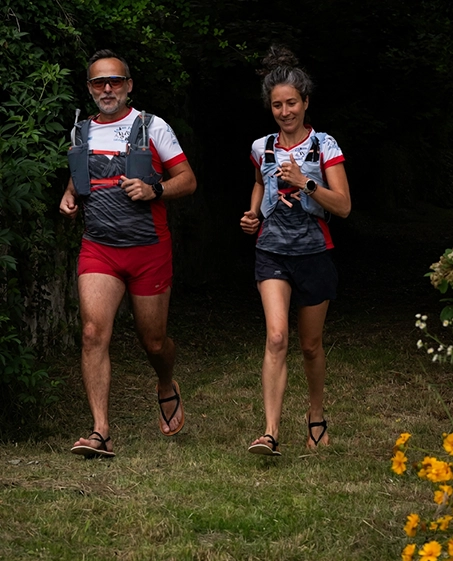 En homme et une femme courant en venant vers l'objectif et portant des sandales minimalistes