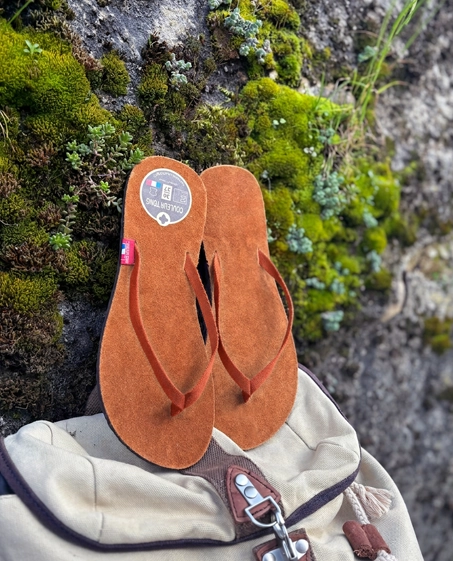Paire de tong cuir ultra légère pour la récupération posée sur un sac à dos